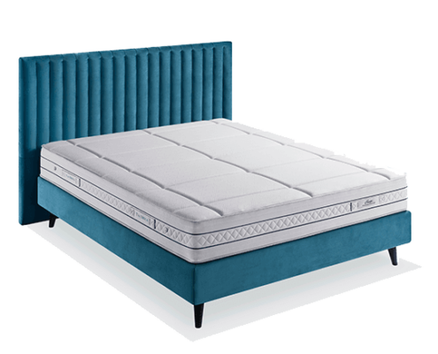 Un cadre de lit en velours bleu sarcelle avec un matelas blanc est élégamment présenté sur un fond uni, rappelant un showroom parisien. Canape Paris by Atelier Bis