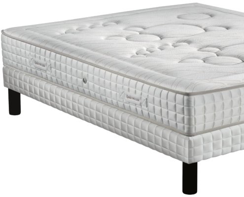 Un matelas et sommier blanc matelassé sur pieds noirs, présentant un motif texturé, offrant une qualité exceptionnelle. Canape Paris by Atelier Bis