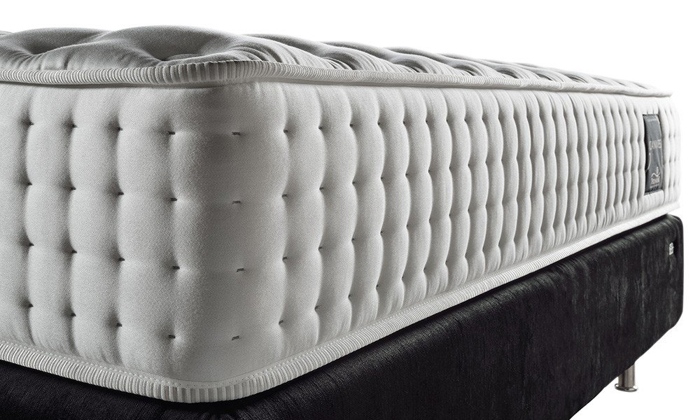 Gros plan d'un matelas blanc capitonné sur un sommier noir chic avec des pieds en métal élégants, dégageant cette élégante ambiance parisienne. Canape Paris by Atelier Bis