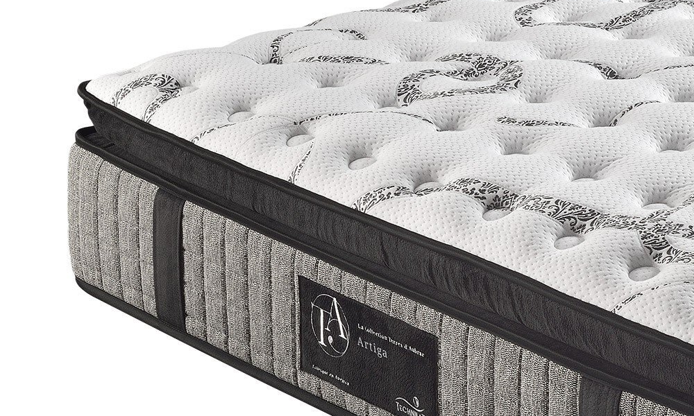 Gros plan d'un coin matelas avec un dessus capitonné blanc et des côtés texturés gris, arborant une étiquette en tissu qui respire la qualité parisienne. Canape Paris by Atelier Bis