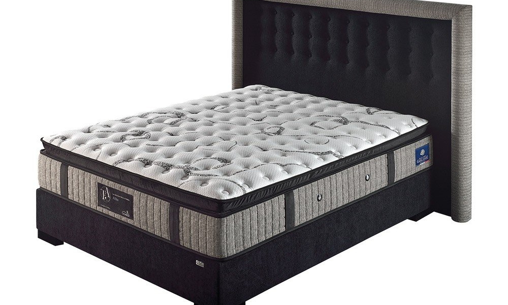 Un matelas au dessus matelassé repose sur un cadre de lit rembourré foncé doté d'une tête de lit haute de style parisien, dégageant un air de qualité. Canape Paris by Atelier Bis