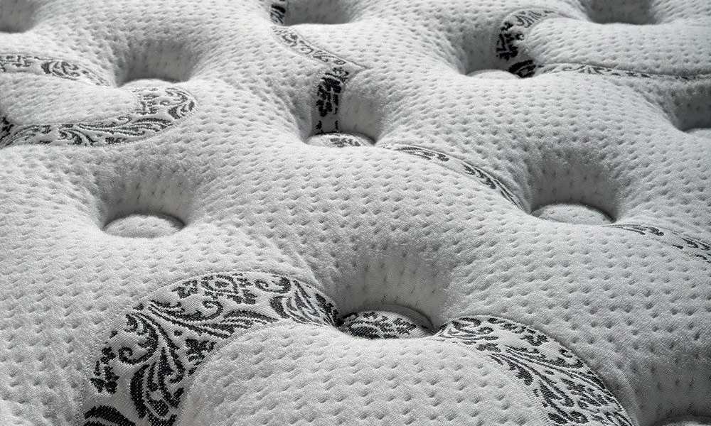 Gros plan d'un matelas blanc aux motifs matelassés et aux motifs floraux noirs décoratifs, offrant une touche d'élégance parisienne. Canape Paris by Atelier Bis