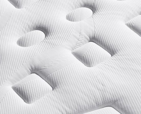 Gros plan d'un matelas blanc avec un motif texturé composé de formes ovales et rectangulaires en relief, incarnant la qualité que vous trouverez dans une boutique parisienne haut de gamme. Canape Paris by Atelier Bis