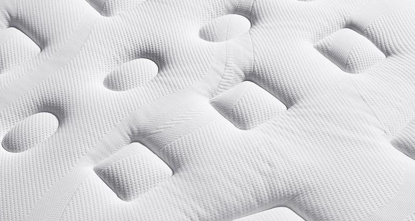 Gros plan d'un matelas blanc avec un motif texturé composé de formes ovales et rectangulaires en relief, incarnant la qualité que vous trouverez dans une boutique parisienne haut de gamme. Canape Paris by Atelier Bis