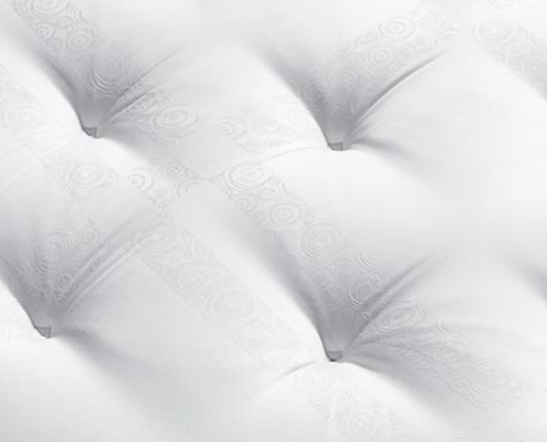 Gros plan d'une surface de matelas capitonnée blanche avec des motifs circulaires texturés sur le tissu, rappelant le design élégant que vous trouveriez dans un Canapé primé chic de Paris. Canape Paris by Atelier Bis