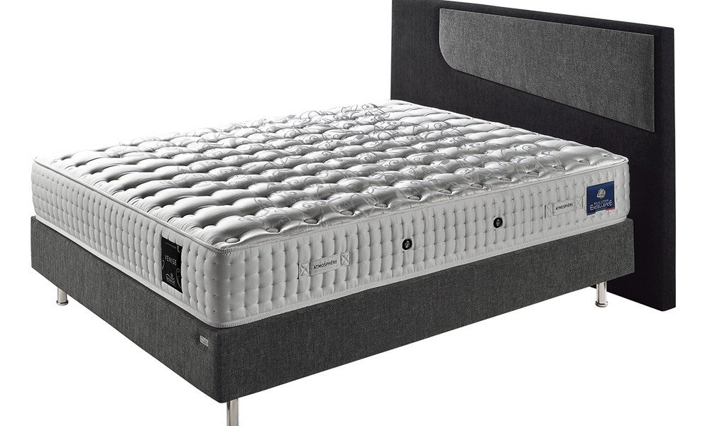 Un matelas luxueux et moderne repose sur un canapé avec un cadre de lit gris foncé, couronné d'une tête de lit expansive rappelant l'élégance chic parisienne. Canape Paris by Atelier Bis