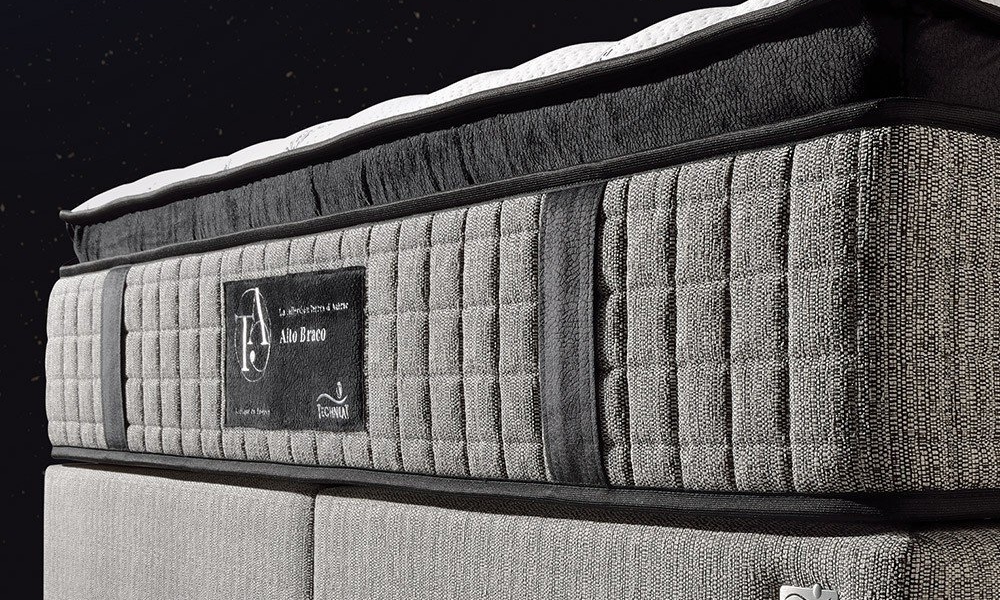 Gros plan d'un matelas gris et noir aux côtés texturés, aux étiquettes de marque et à la qualité exceptionnelle, sur fond noir épuré, rappelant le style parisien chic. Canape Paris by Atelier Bis