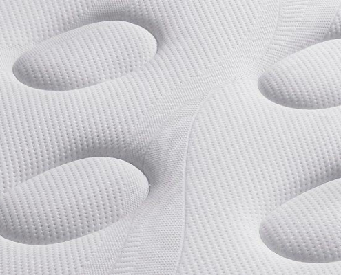 Gros plan d'un matelas blanc aux motifs circulaires texturés et au tissu matelassé, reposant élégamment sur un canapé élégant, parfaitement adapté à un appartement parisien. Canape Paris by Atelier Bis