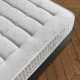 Un matelas blanc au motif matelassé repose sur un cadre de lit sombre, dégageant un air de qualité parisienne tout en complétant le parquet à chevrons. Canape Paris by Atelier Bis