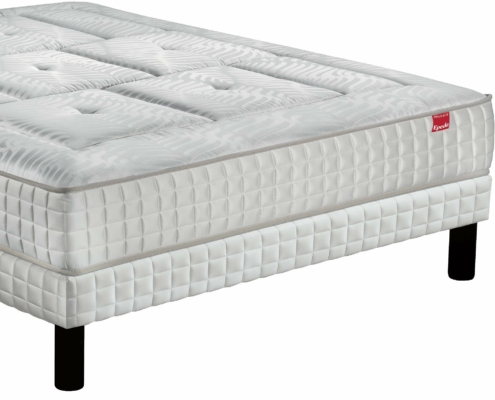 Un matelas blanc au motif texturé repose élégamment sur un cadre de lit aux pieds noirs, rappelant le style parisien chic. Canape Paris by Atelier Bis