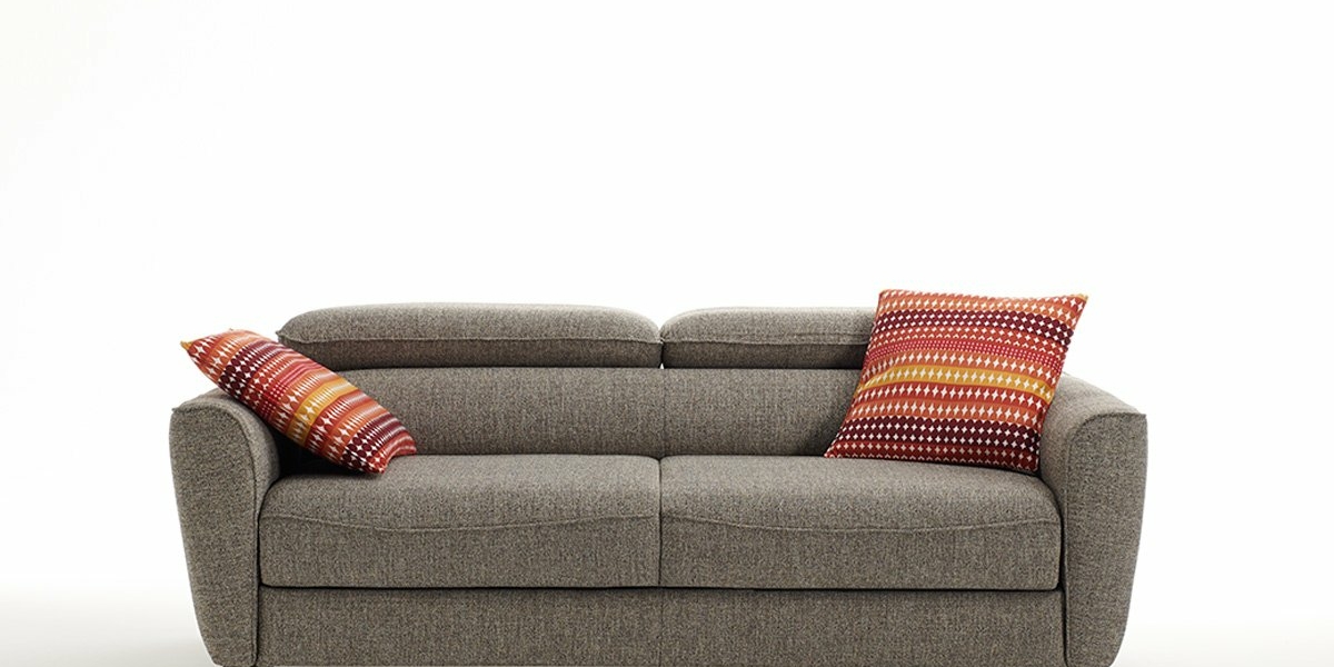 Un canapé gris orné de deux coussins à motifs rouges, posés sur un fond blanc uni, dégage une touche de qualité parisienne. Canape Paris by Atelier Bis