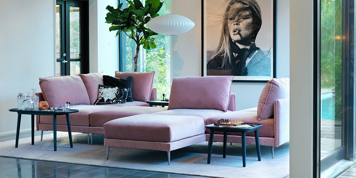 Salon moderne avec un canapé rose chic, deux tables d'appoint, une grande plante et un portrait en noir et blanc sur le mur. Un style parfait, comme s'il sortait tout droit d'un showroom de designer. Canape Paris by Atelier Bis