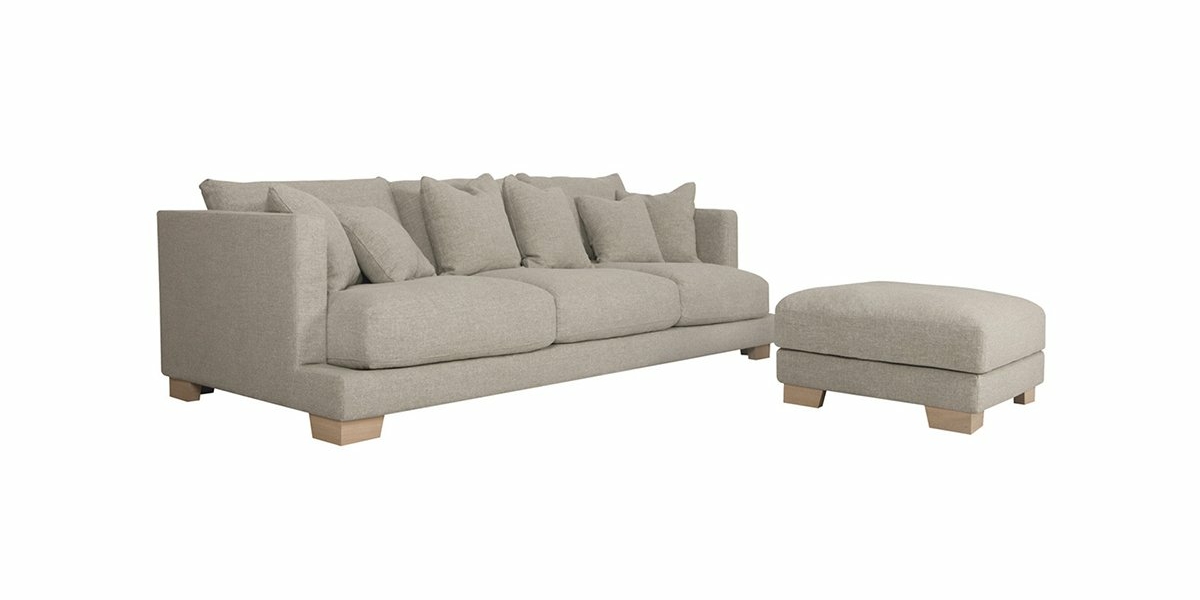 Canapé beige de qualité parisienne avec pouf assorti sur pieds en bois clair, sur fond blanc immaculé. Canape Paris by Atelier Bis