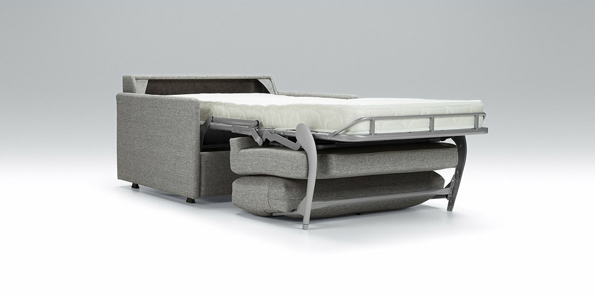 Dans un showroom parisien, un canapé-lit gris est élégamment présenté, partiellement déplié pour révéler son matelas sur un cadre en métal robuste sur un fond uni. Canape Paris by Atelier Bis