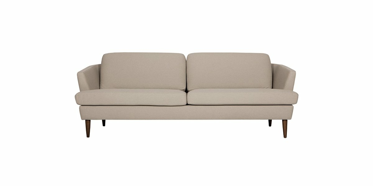 Canapé beige moderne du milieu du siècle avec pieds en bois sur fond blanc, mettant en valeur une qualité intemporelle. Canape Paris by Atelier Bis