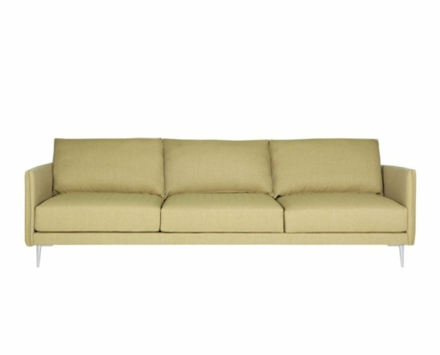 Dans un showroom immaculé, un canapé vert clair au design minimaliste et aux pieds argentés épurés se détache élégamment sur le fond blanc. Canape Paris by Atelier Bis