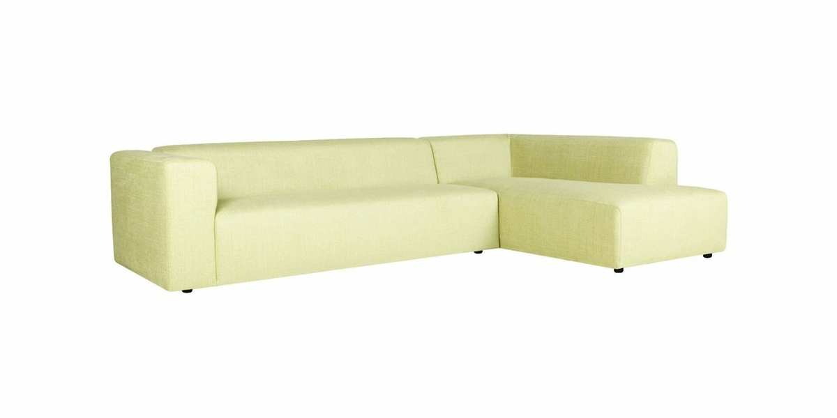 Canapé vert clair en forme de L avec un dossier bas et des accoudoirs en bloc, sur fond blanc immaculé, dégageant un charme parisien chic. Canape Paris by Atelier Bis