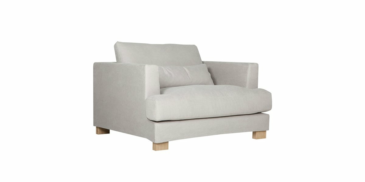 Un fauteuil gris clair avec des pieds en bois et un coussin assorti, offrant une touche de qualité proche d'un canapé fin. Canape Paris by Atelier Bis