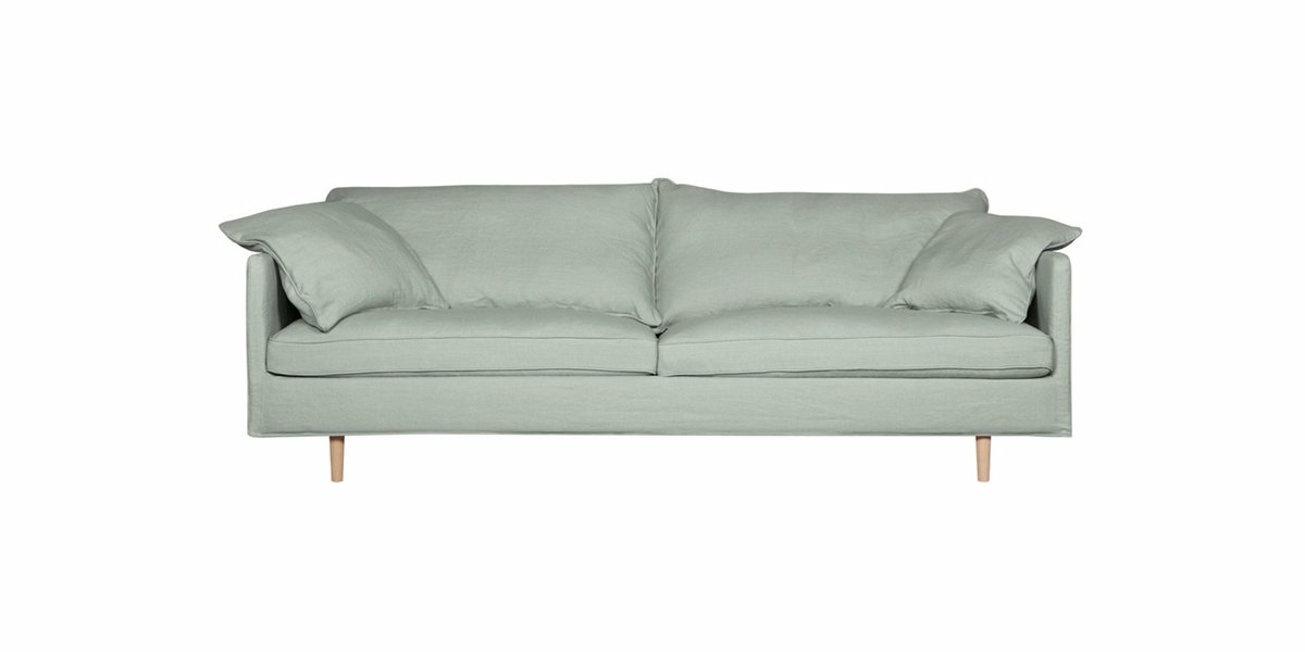 Un canapé vert clair avec deux grands coussins et des pieds en bois, vu de face, respire la qualité parisienne sur un fond blanc. Canape Paris by Atelier Bis