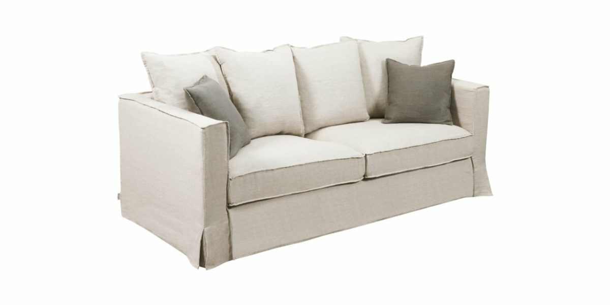 Un canapé beige avec cinq coussins – trois beiges et deux gris – offre un confort chic rappelant le style parisien, sur fond blanc immaculé. Canape Paris by Atelier Bis