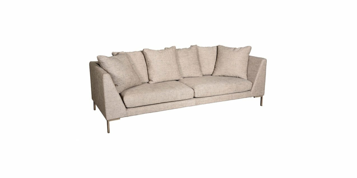 Un canapé beige et moderne avec plusieurs coussins et des pieds fins se pose élégamment sur un fond blanc, incarnant la simplicité chic que vous trouverez dans une salle d'exposition haut de gamme. Canape Paris by Atelier Bis