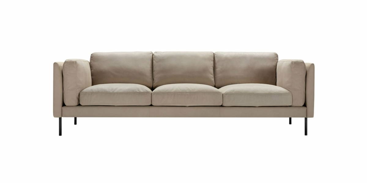 Un canapé beige à trois places avec des pieds noirs élégants est élégamment présenté sur un fond blanc immaculé, parfait pour toute salle d'exposition moderne. Canape Paris by Atelier Bis