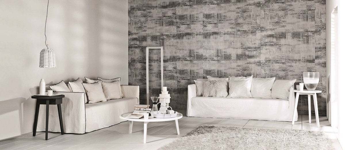 Salon minimaliste beige et gris ressemblant à un élégant showroom parisien, avec des canapés, une table basse ronde et du papier peint texturé. Canape Paris by Atelier Bis