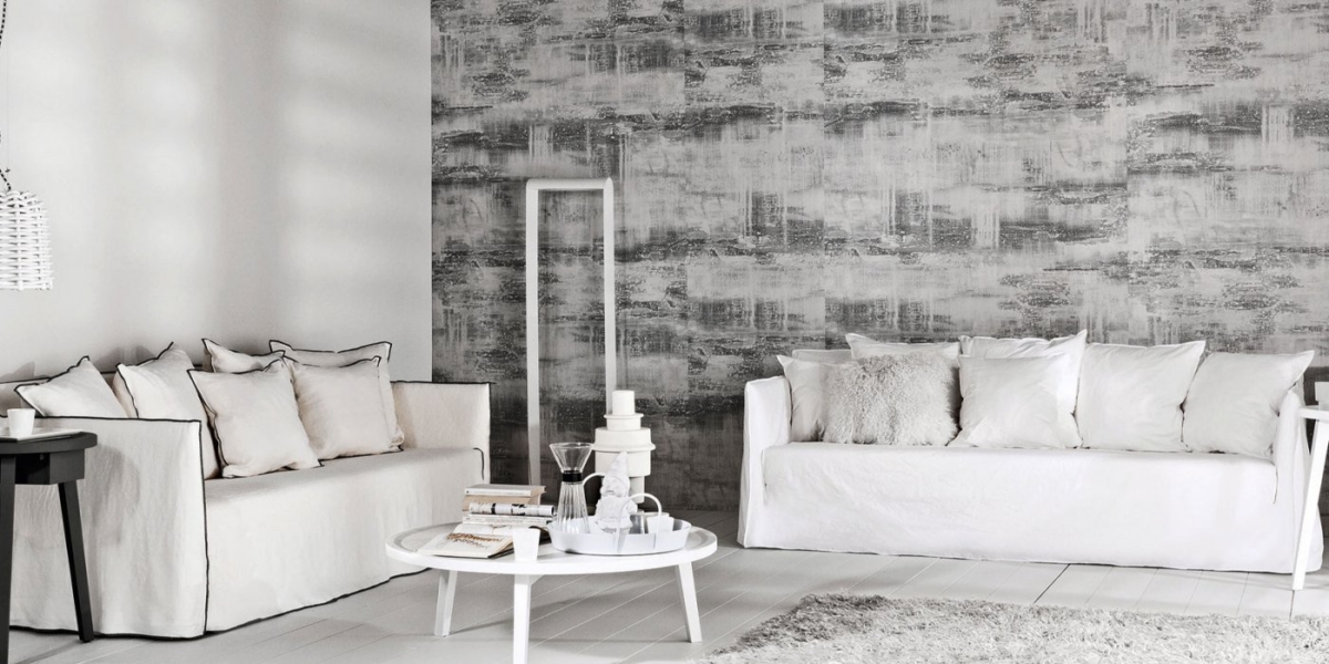 Un salon minimaliste doté d'un canapé blanc de qualité, d'un papier peint gris abstrait rappelant le chic parisien et d'une table basse ronde ornée d'objets de décoration de bon goût. Canape Paris by Atelier Bis