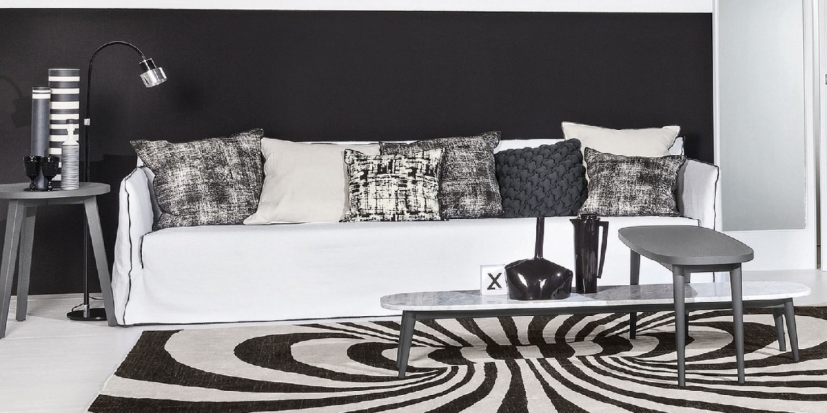 Entrez dans un salon moderne qui pourrait rivaliser avec n'importe quelle salle d'exposition, avec un décor noir et blanc, un canapé blanc moelleux orné de coussins et des tables basses élégantes. Le tapis à motifs ajoute de la texture et de la profondeur, promettant à la fois confort et qualité. Canape Paris by Atelier Bis