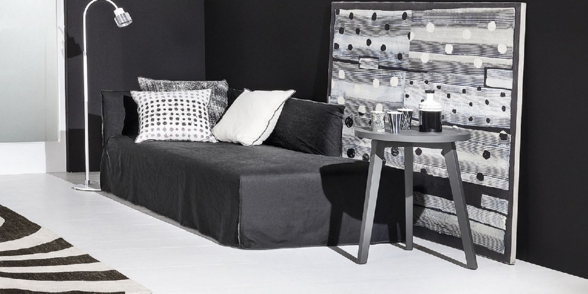 Salon moderne noir et blanc avec un canapé, des œuvres d'art monochromes et une table d'appoint avec une lampe et un décor qui respire la qualité d'une salle d'exposition. Canape Paris by Atelier Bis