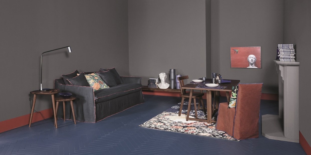 Découvrez un espace de vie et de salle à manger moderne de qualité showroom, avec des murs sombres, un sol à chevrons bleu, un canapé confortable et une table élégante ornée d'objets décoratifs. Canape Paris by Atelier Bis