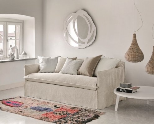 Une touche parisienne chic orne le salon minimaliste avec un canapé beige, des œuvres d'art murales abstraites et des luminaires suspendus en osier, le tout conçu pour la qualité. Le tapis à motifs colorés ajoute du dynamisme à cet espace élégant. Canape Paris by Atelier Bis