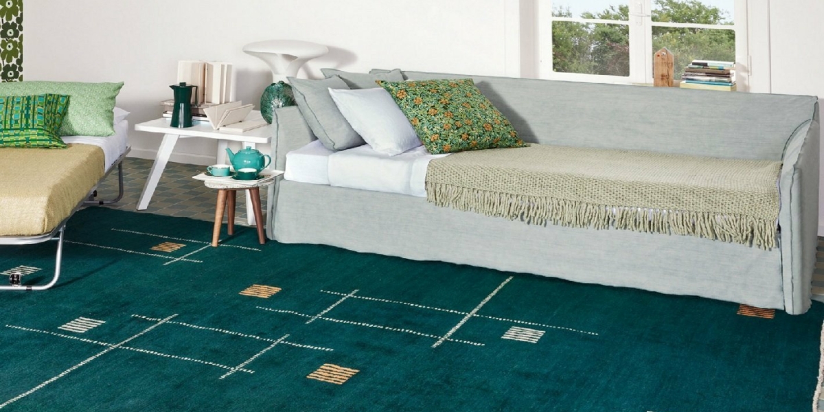 Salon cosy rappelant un showroom parisien, avec un canapé gris clair, un tapis vert à motifs, une table basse chic et une fenêtre avec une vue exquise sur les arbres, le tout rayonnant d'une qualité irréprochable. Canape Paris by Atelier Bis