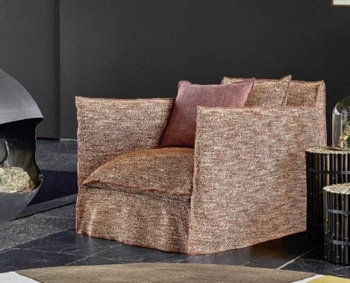 Dans une pièce moderne d'inspiration parisienne, un fauteuil marron s'associe sans effort à des tables rondes en bois, le tout adossé à un mur sombre orné d'une élégante cheminée noire. C'est comme si vous pénétriez dans un showroom exclusif d'élégance et de confort. Canape Paris by Atelier Bis