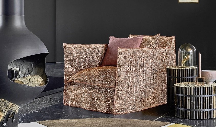 Dans une pièce moderne d'inspiration parisienne, un fauteuil marron s'associe sans effort à des tables rondes en bois, le tout adossé à un mur sombre orné d'une élégante cheminée noire. C'est comme si vous pénétriez dans un showroom exclusif d'élégance et de confort. Canape Paris by Atelier Bis