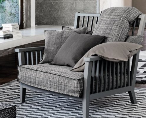 Fauteuil rembourré gris à motif à carreaux, rappelant un style parisien chic, posé sur un tapis géométrique noir et blanc dans une pièce moderne. Canape Paris by Atelier Bis