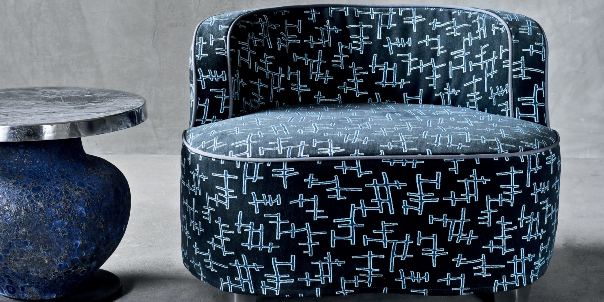 Élégant fauteuil noir au motif abstrait rappelant le chic parisien, joliment associé à une petite table d'appoint ronde dotée d'une base texturée. Canape Paris by Atelier Bis