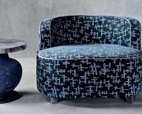 Élégant fauteuil noir au motif abstrait rappelant le chic parisien, joliment associé à une petite table d'appoint ronde dotée d'une base texturée. Canape Paris by Atelier Bis