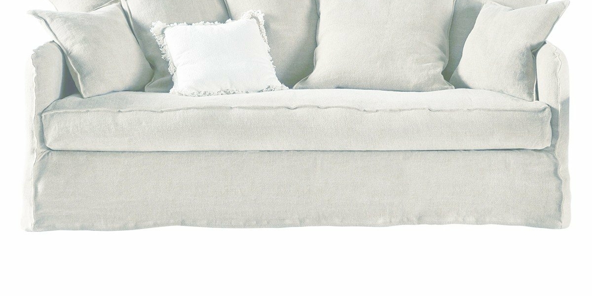 Un canapé gris clair avec plusieurs coussins, dont un avec un bord à volants, respire la qualité parisienne. Canape Paris by Atelier Bis