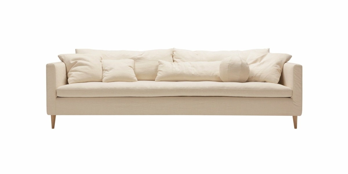 Canapé couleur crème d'une qualité exceptionnelle, orné de multiples coussins, sur fond blanc immaculé. Parfait pour tout showroom recherchant élégance et confort. Canape Paris by Atelier Bis