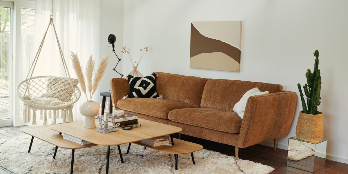 Un salon élégant avec canapé de qualité, table en bois, chaise suspendue et œuvres d'art abstraites. Les murs blancs et la décoration chaleureuse offrent une touche d'élégance parisienne. Canape Paris by Atelier Bis