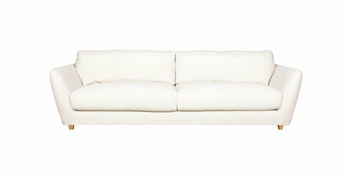 Un canapé beige deux places avec des coussins moelleux et des pieds en bois, présenté dans un décor de salle d'exposition sur un fond blanc, illustrant à la fois le style et la qualité. Canape Paris by Atelier Bis