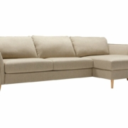 Canapé sectionnel beige clair avec pieds en bois, doté de trois coussins et d'une méridienne droite, sur fond blanc, rappelant l'élégance parisienne. Canape Paris by Atelier Bis