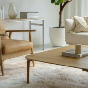 Salon moderne avec fauteuil beige, canapé blanc, table basse en bois et tapis moelleux. La décoration simple et la verdure ajoutent une touche de qualité parisienne. Canape Paris by Atelier Bis