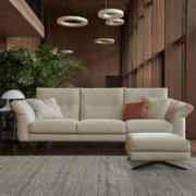 Un canapé sectionnel beige dans une pièce parisienne moderne, orné de grandes plantes, de suspensions et d'un tapis texturé, crée une ambiance digne d'un showroom. Canape Paris by Atelier Bis