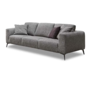 Canapé moderne gris avec trois coussins d'assise, deux coussins gris et un coussin foncé sur fond blanc tel que présenté dans notre showroom parisien. Canape Paris by Atelier Bis