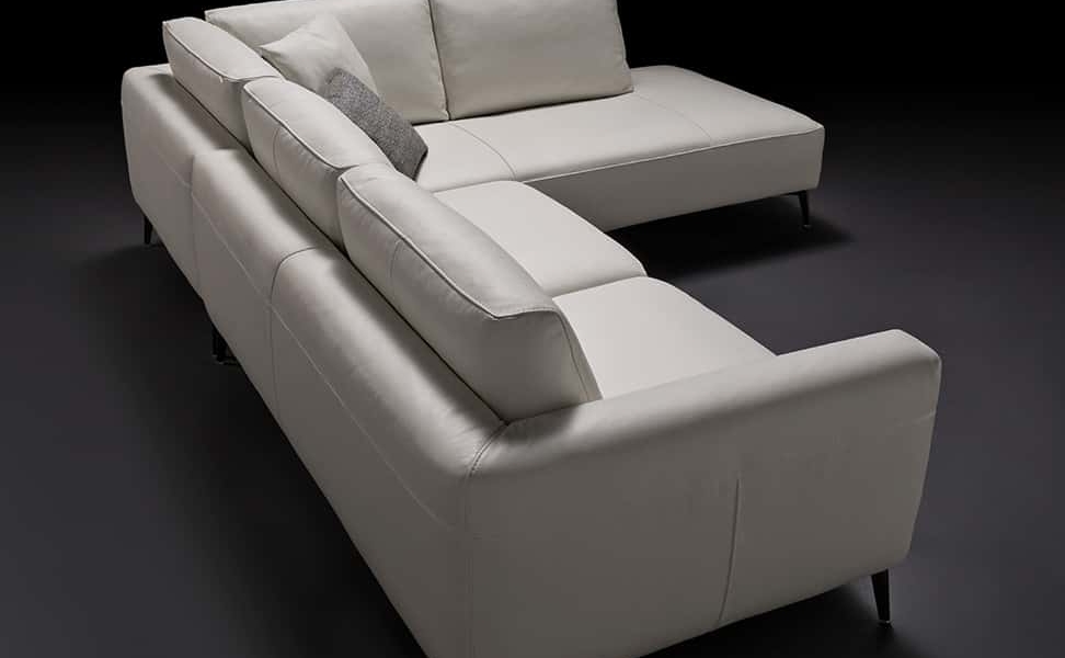 Un canapé sectionnel gris élégant et moderne avec des pieds noirs sur un fond sombre, accentué par plusieurs coussins moelleux. Canape Paris by Atelier Bis