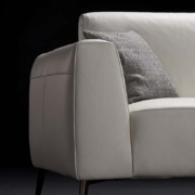 Un canapé gris clair avec un coussin en tweed sur le côté gauche se dresse gracieusement sur un fond noir, incarnant une qualité inégalée. Canape Paris by Atelier Bis