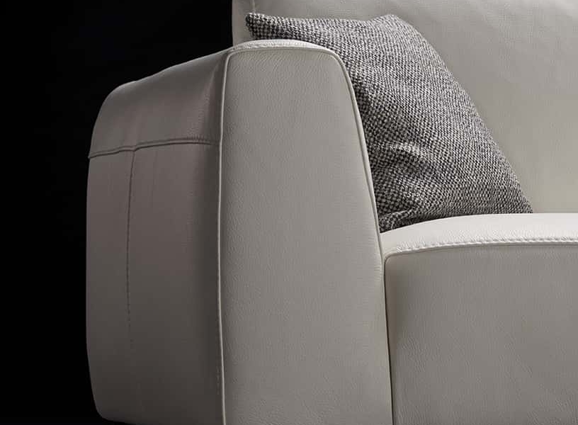 Un canapé gris clair avec un coussin en tweed sur le côté gauche se dresse gracieusement sur un fond noir, incarnant une qualité inégalée. Canape Paris by Atelier Bis