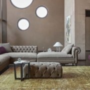 Salon sophistiqué avec un canapé sectionnel taupe, des chaises violettes, des fenêtres rondes et un tapis texturé qui respire la qualité. Canape Paris by Atelier Bis